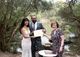 Sylvie and the bride and groom holding the marriage certificate in front of the lake.